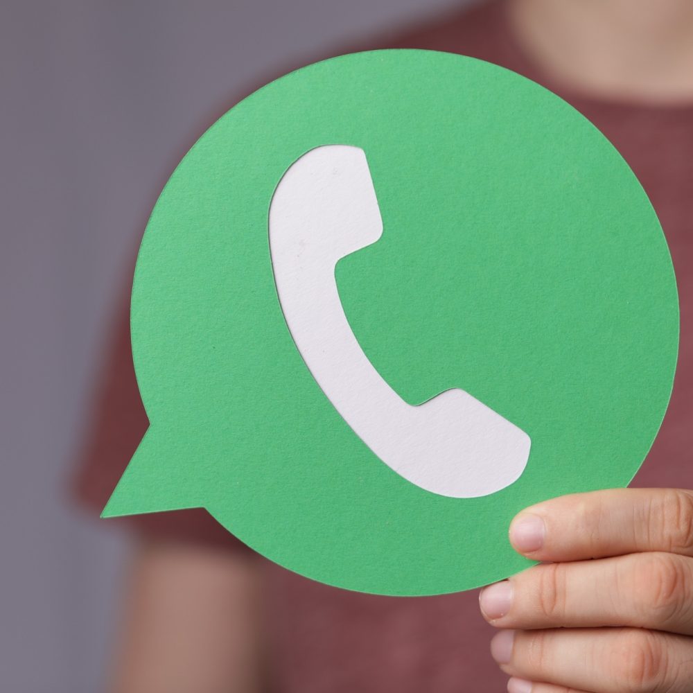 A hand holding a green paper phone icon